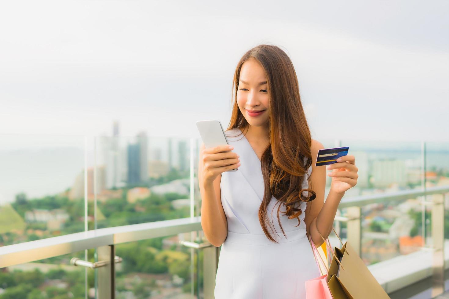 retrato, hermoso, joven, mujer asiática, feliz, y, sonrisa, con, tarjeta de crédito, y, móvil, o, teléfono inteligente, y, bolsa de compras foto