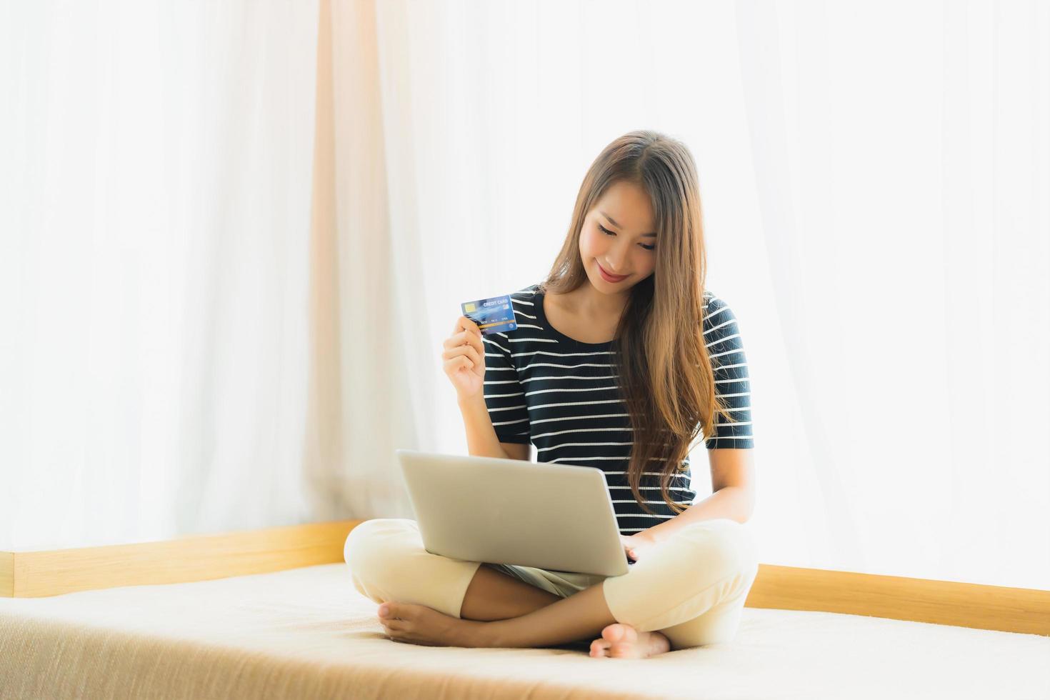 Portrait beautiful young asian woman using computer notebook or laptop with credit card for shopping photo