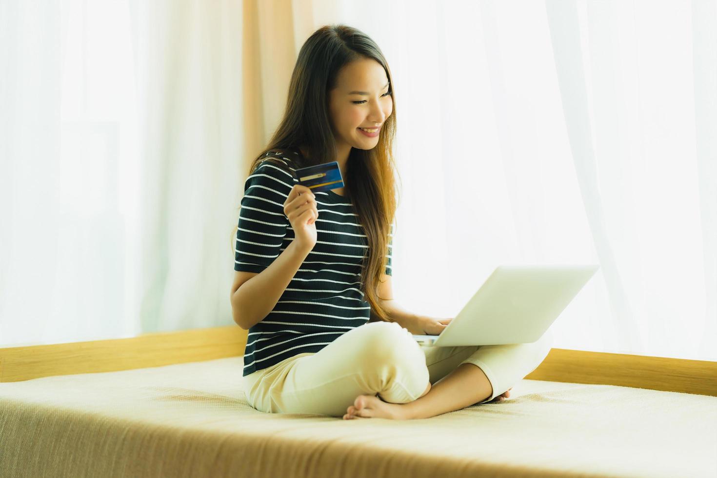 Portrait beautiful young asian woman using computer notebook or laptop with credit card for shopping photo