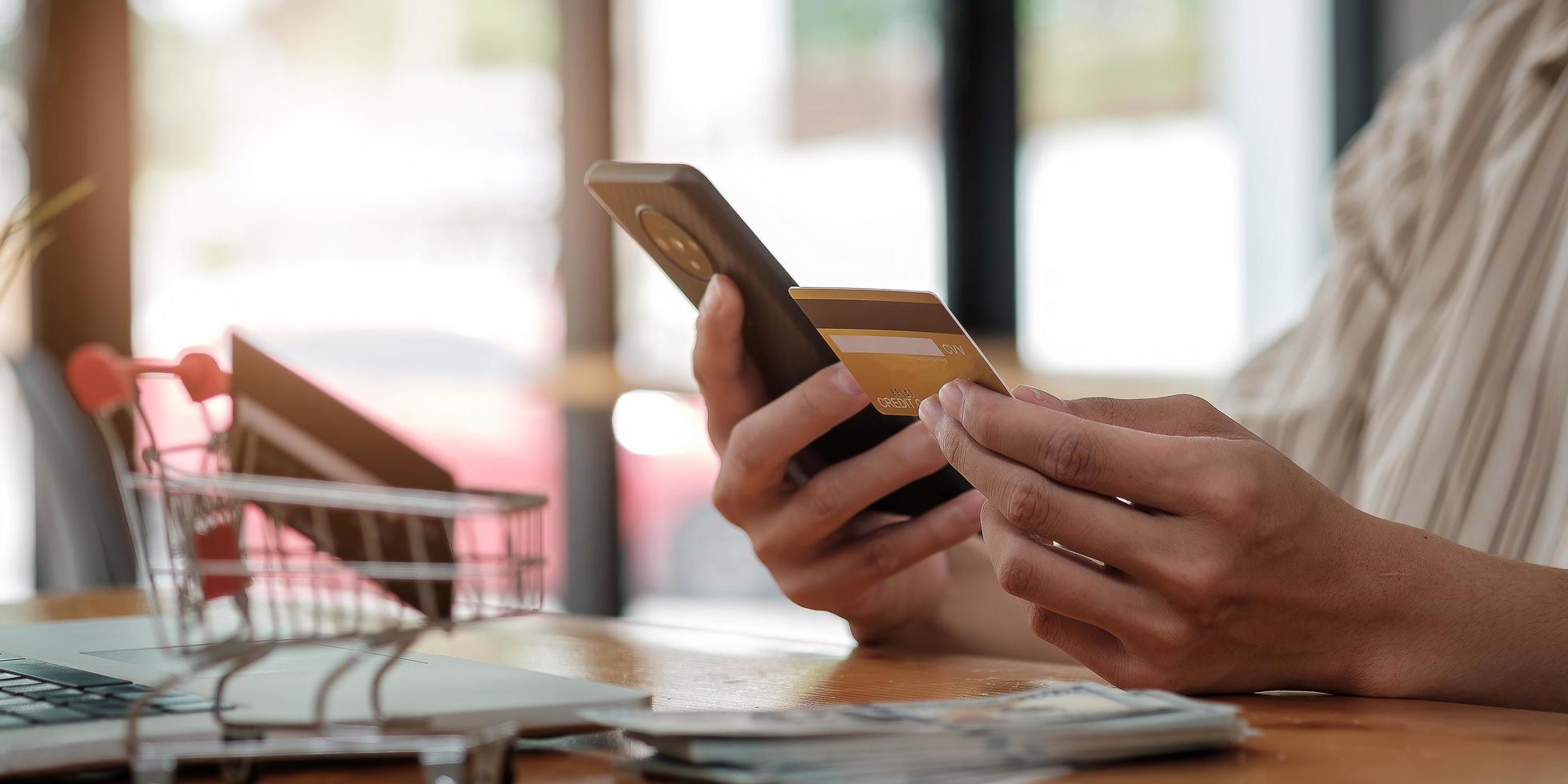 Pago en línea, manos del hombre sosteniendo un teléfono inteligente con tarjeta de crédito para compras en línea. foto