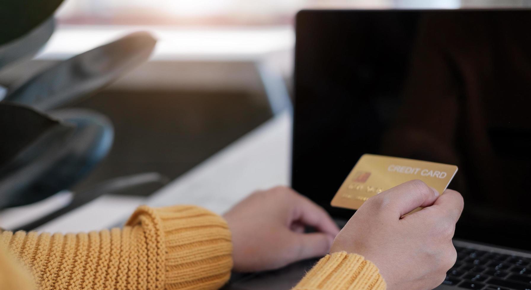 Pago en línea, manos del joven usando la computadora y mano que sostiene la tarjeta de crédito para compras en línea foto