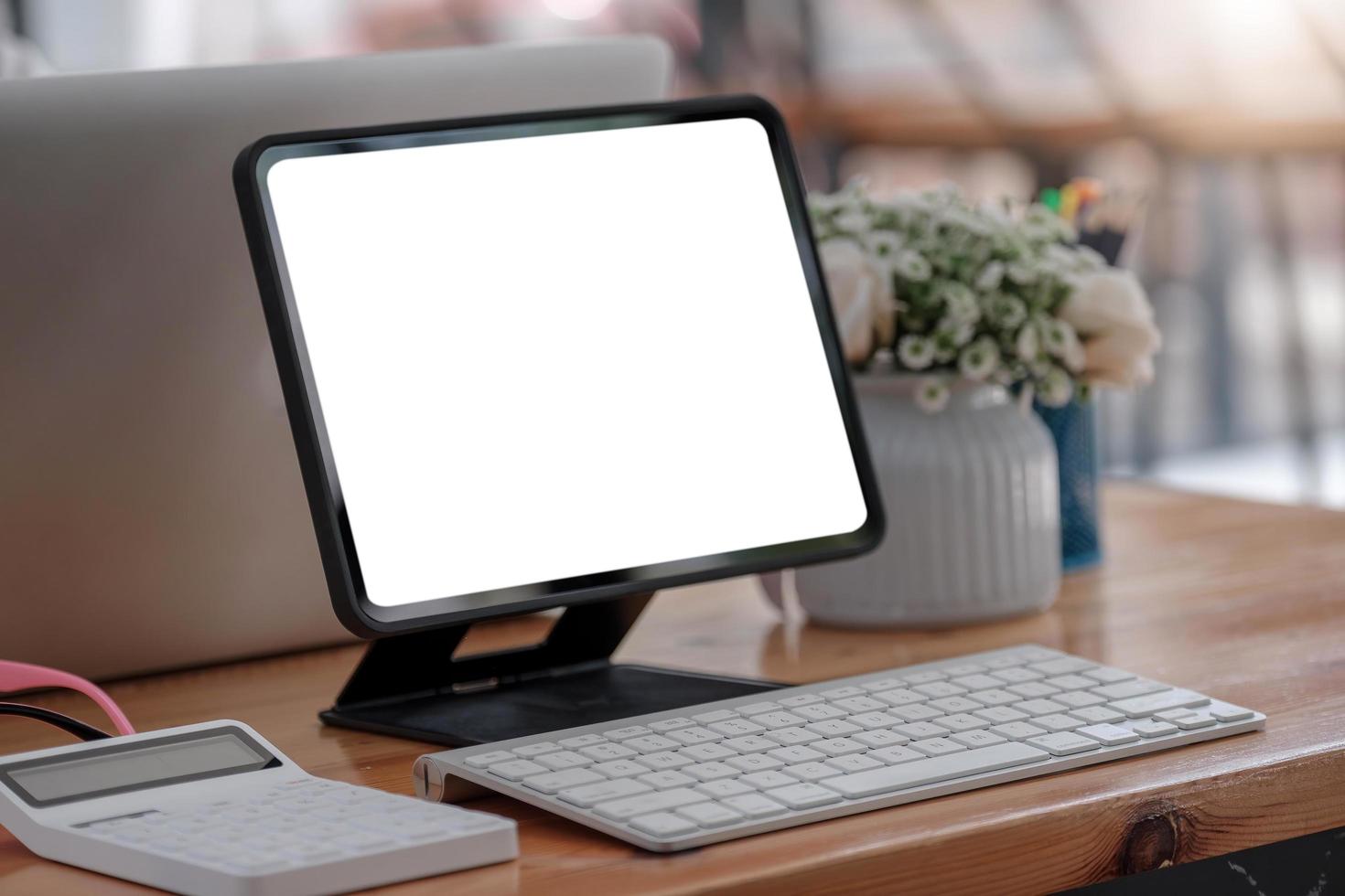 Ordenador portátil de pantalla en blanco y fondo del espacio de trabajo del cartel en la oficina moderna foto