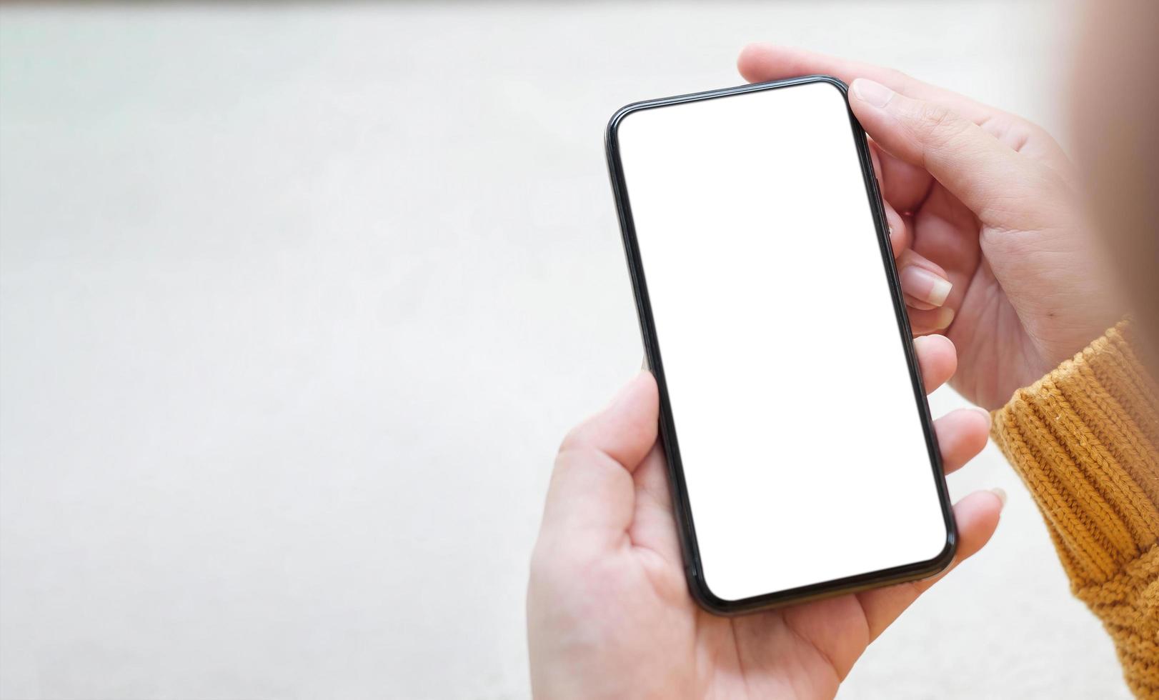 Mockup image blank white screen cell phone.women hand holding texting using mobile on desk at home office photo