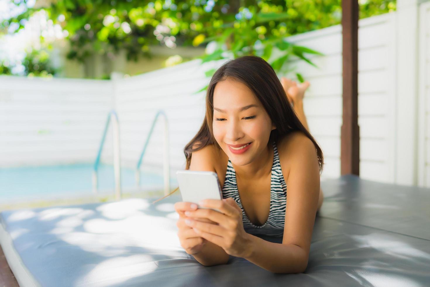 Portrait beautiful young asian woman happy smile talk mobile phone around swimming pool photo