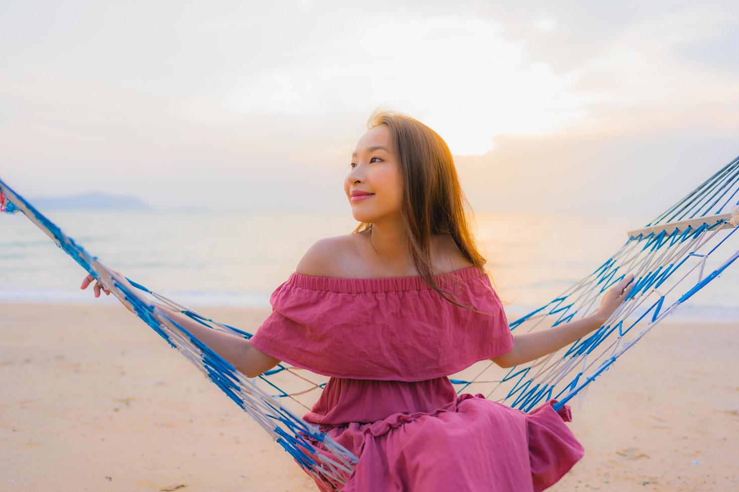 retrato, hermoso, joven, mujer asiática, sentado, en, el, hamaca, con, sonrisa, feliz, neary, playa, mar y océano foto