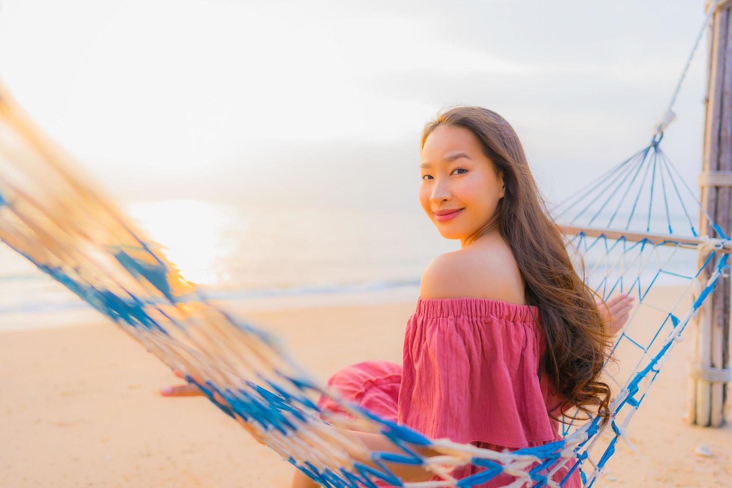 retrato, hermoso, joven, mujer asiática, sentado, en, el, hamaca, con, sonrisa, feliz, neary, playa, mar y océano foto