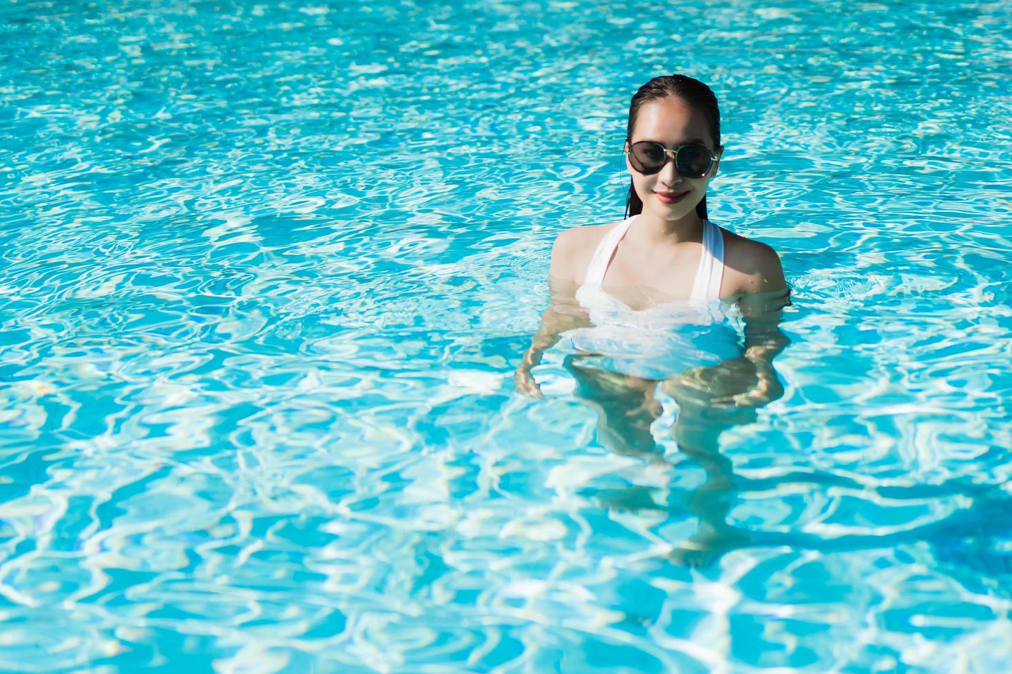 Beautiful young asian woman happy and smile in swimming pool for relax travel and vacation photo