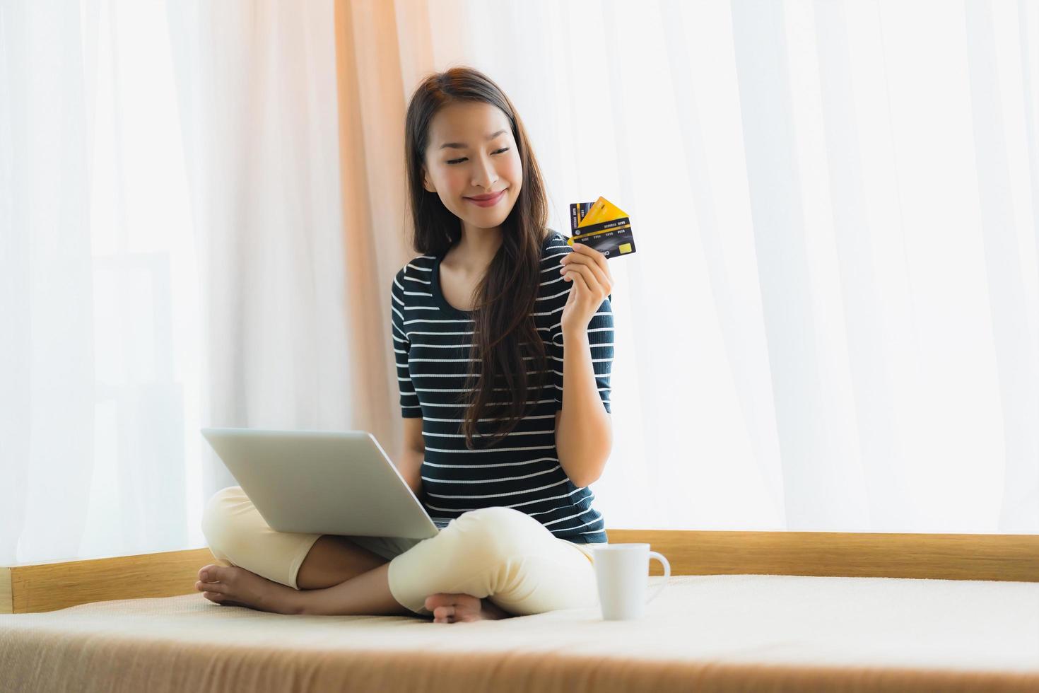 Portrait beautiful young asian woman using computer notebook or laptop with credit card for shopping photo