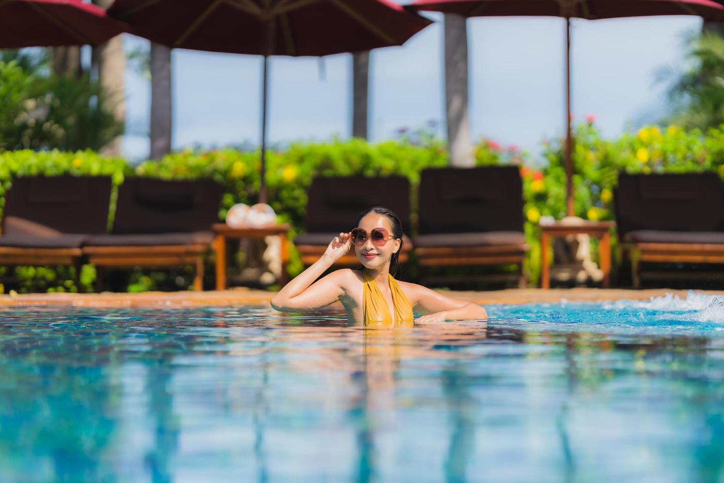 retrato, hermoso, joven, mujer asiática, ocio, relajarse, sonrisa, y, feliz, alrededor, piscina, en, hotel resort foto
