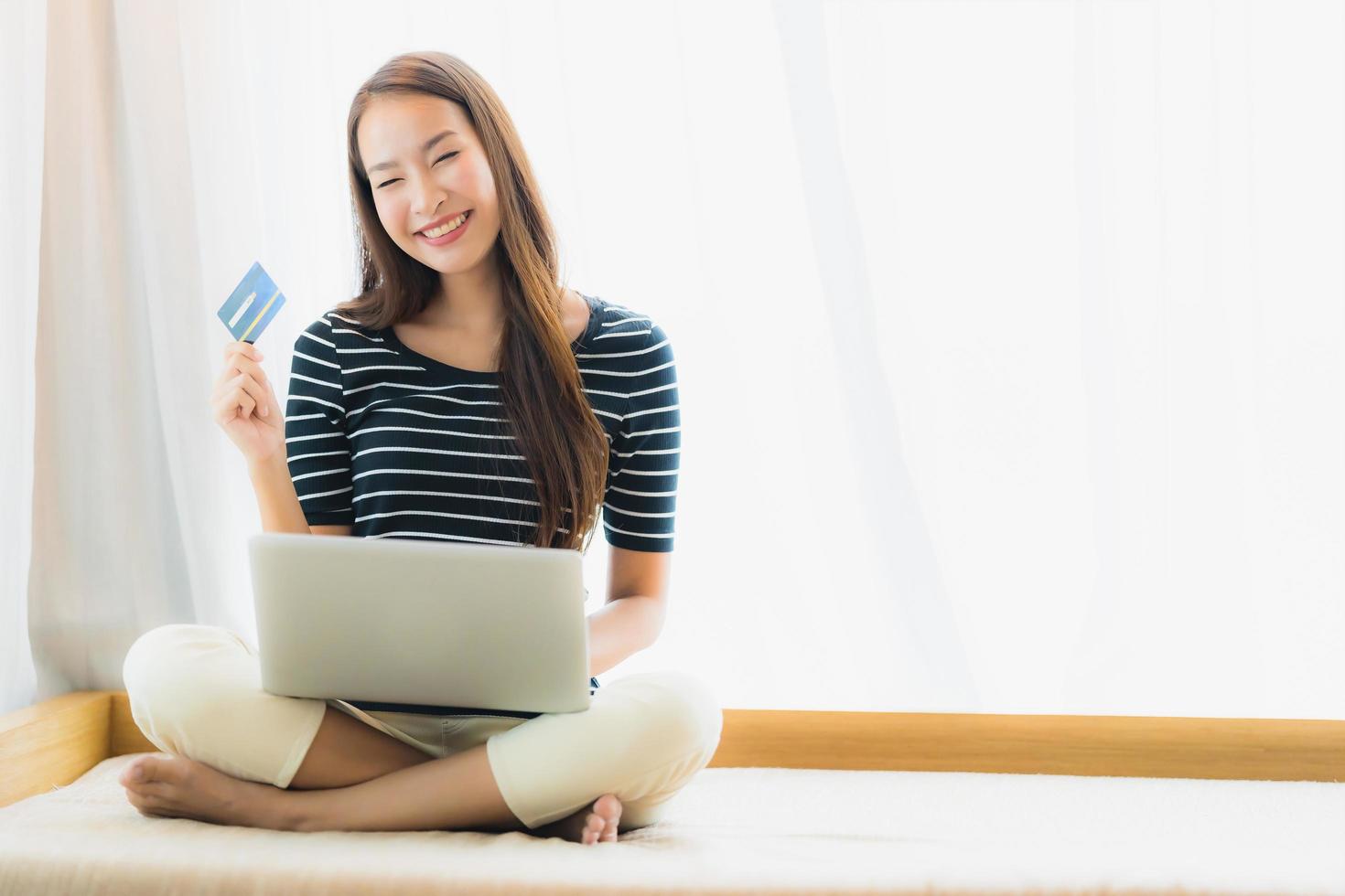 Portrait beautiful young asian woman using computer notebook or laptop with credit card for shopping photo