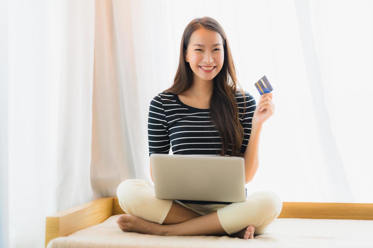 Portrait beautiful young asian woman using computer notebook or laptop with credit card for shopping photo