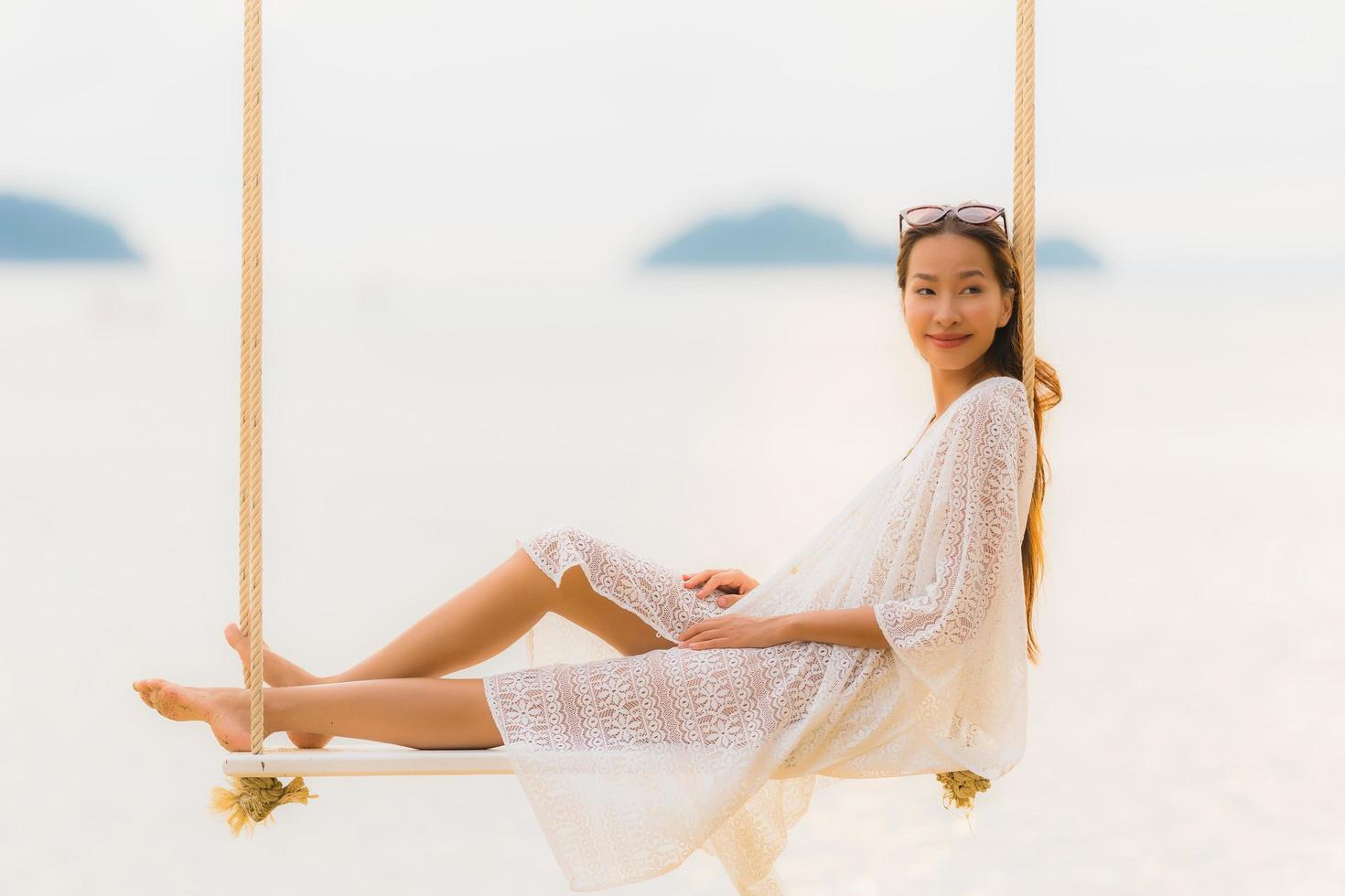 Portrait beautiful young asian woman sitting on the swing around beach sea ocean for relax photo