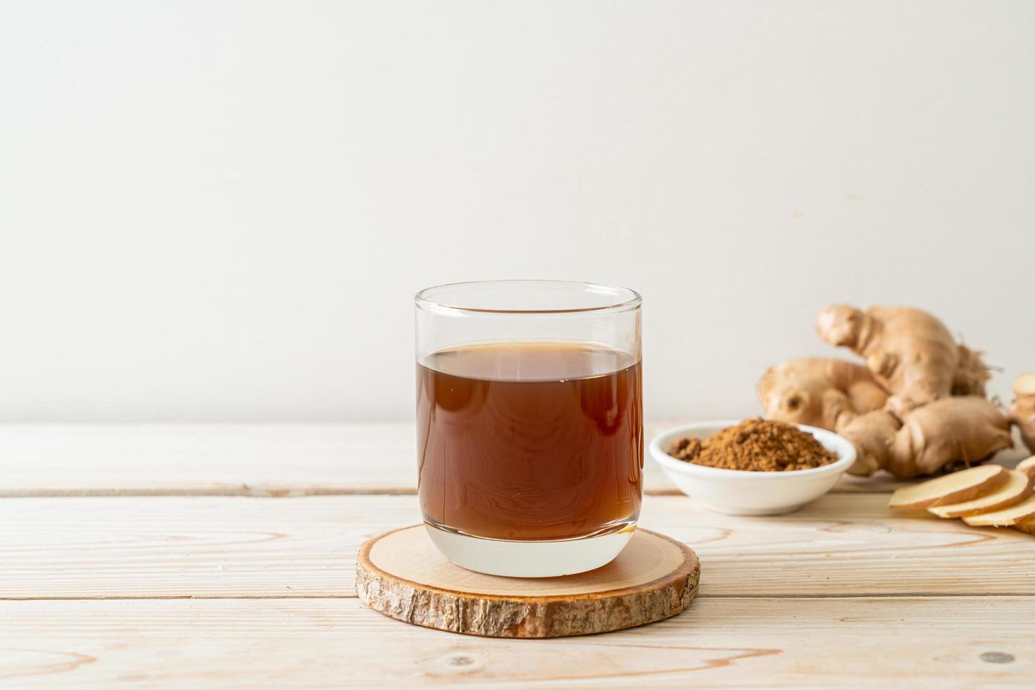 Hot and sweet ginger juice glass with ginger roots - Healthy drink style photo