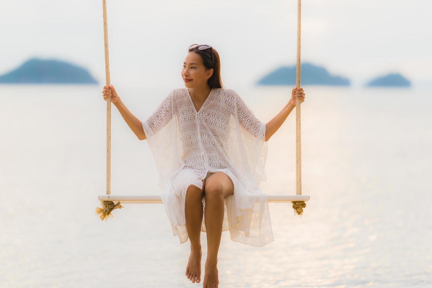 Portrait beautiful young asian woman sitting on the swing around beach sea ocean for relax photo