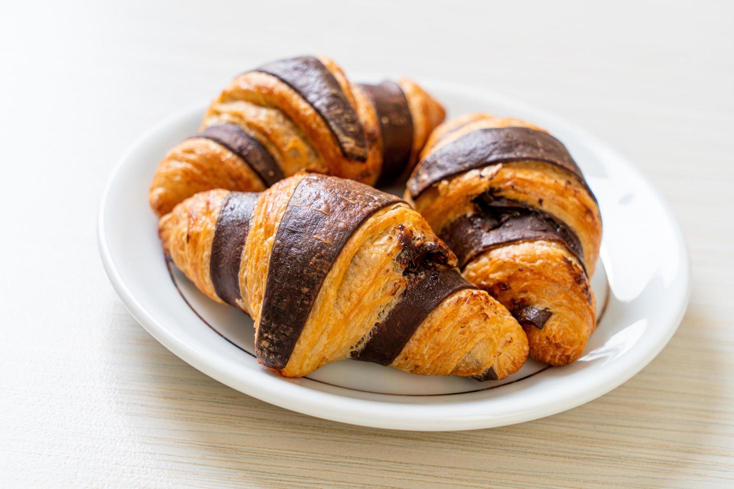 Fresh croissant with chocolate on plate photo