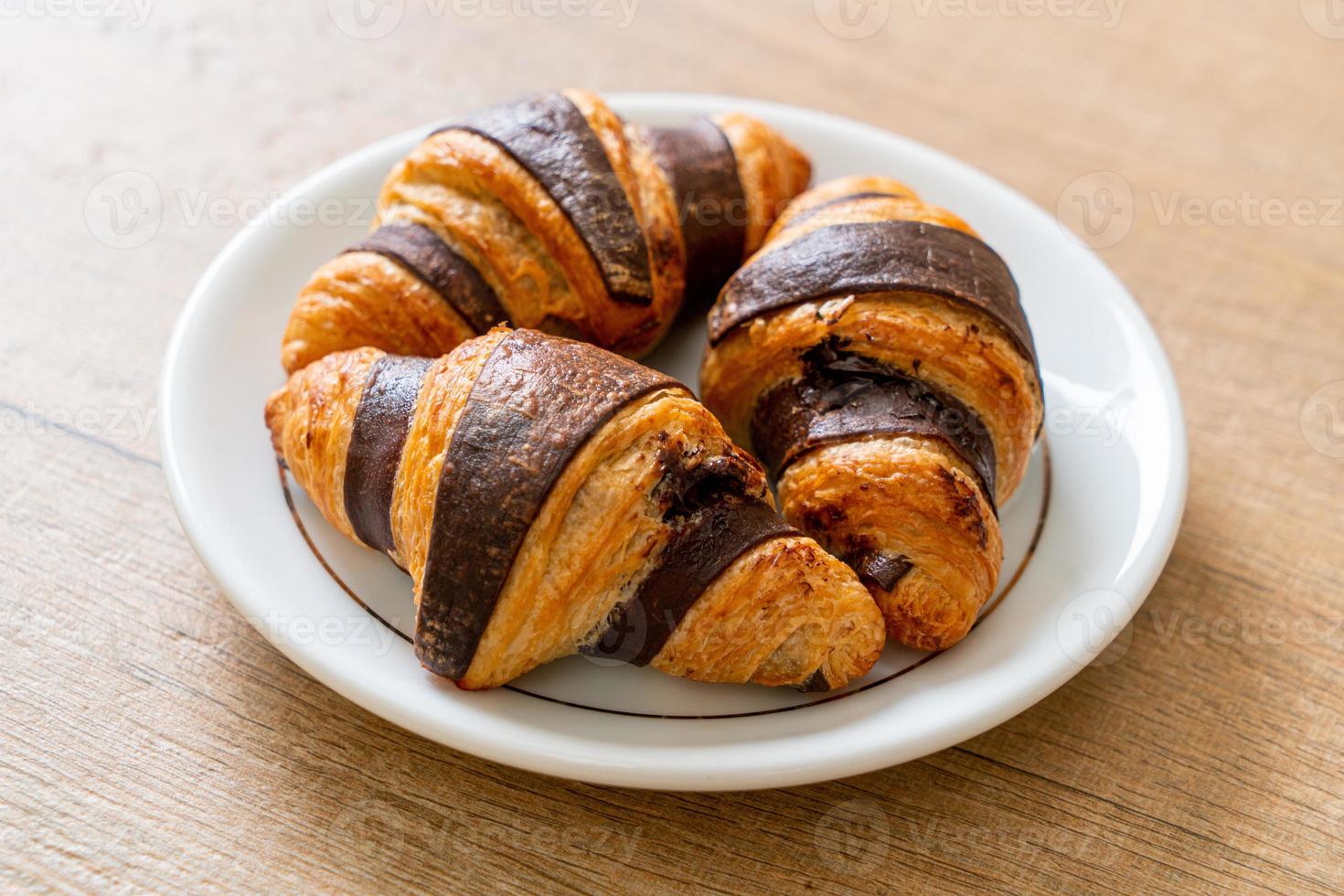 Fresh croissant with chocolate on plate photo