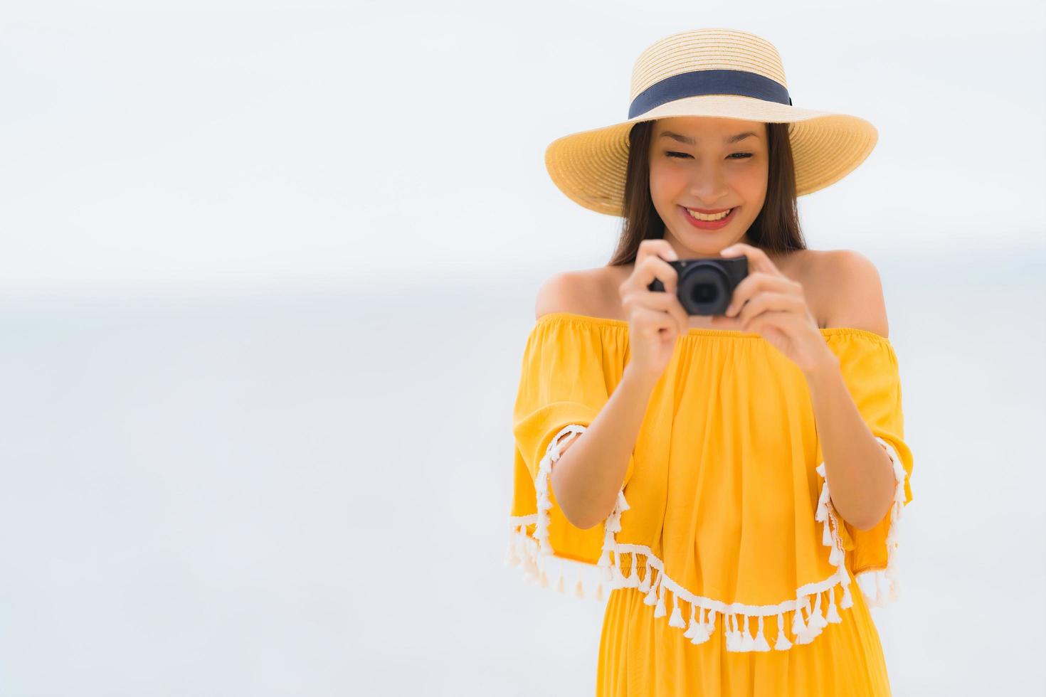 Portrait beautiful asian woman wear hat with smile happy leisure in take a photo on the beach and sea in holiday vacation