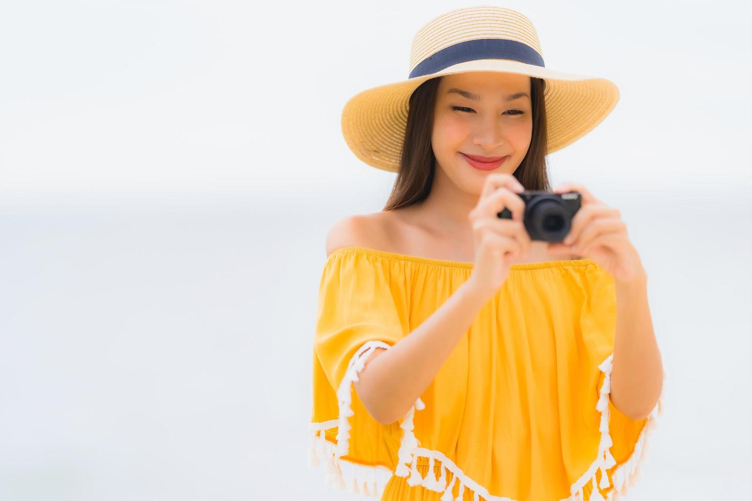 Retrato hermosa mujer asiática usar sombrero con sonrisa feliz ocio en tomar una foto en la playa y el mar en vacaciones de vacaciones