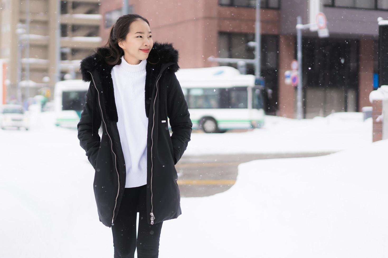 Hermosa joven asiática sonriendo feliz para viajar en la temporada de invierno con nieve foto