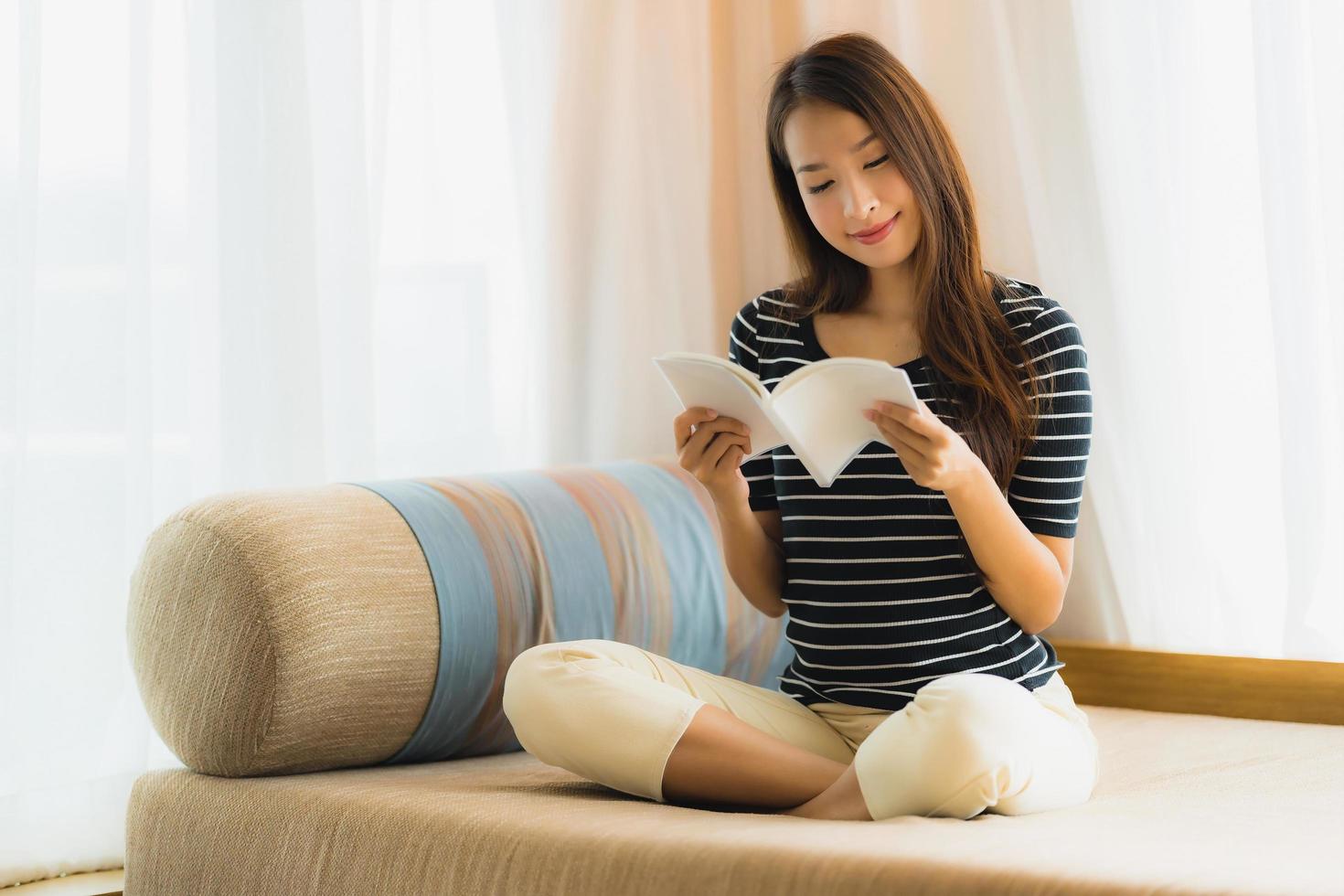 Portrait beautiful young asian woman reading book in on sofa in living room area photo