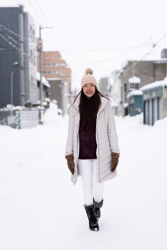 Hermosa joven asiática sonriendo feliz para viajar en la temporada de invierno con nieve foto