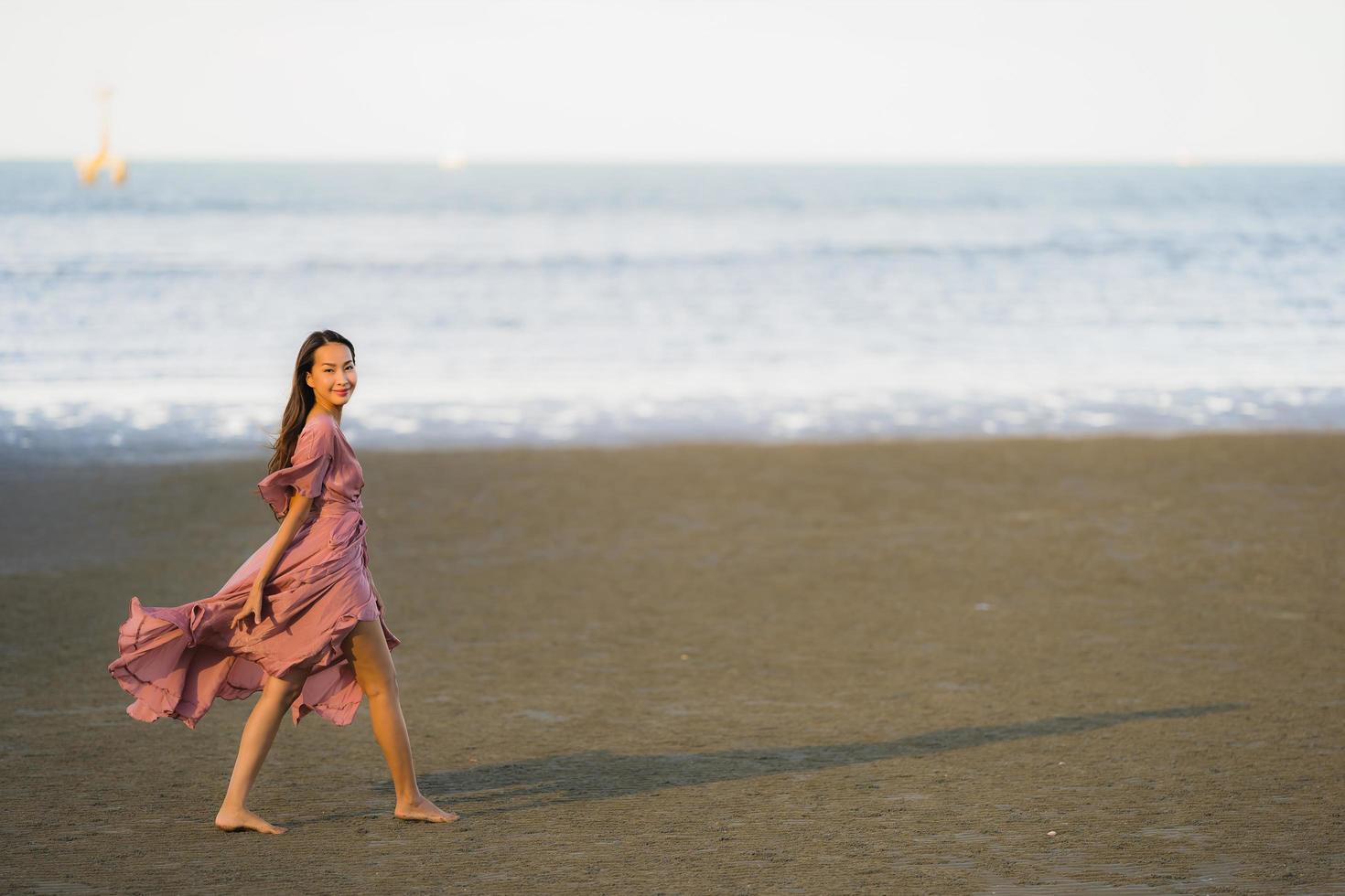 retrato, joven, hermoso, mujer asiática, caminar, sonrisa, y, feliz, en, el, playa, mar y océano foto