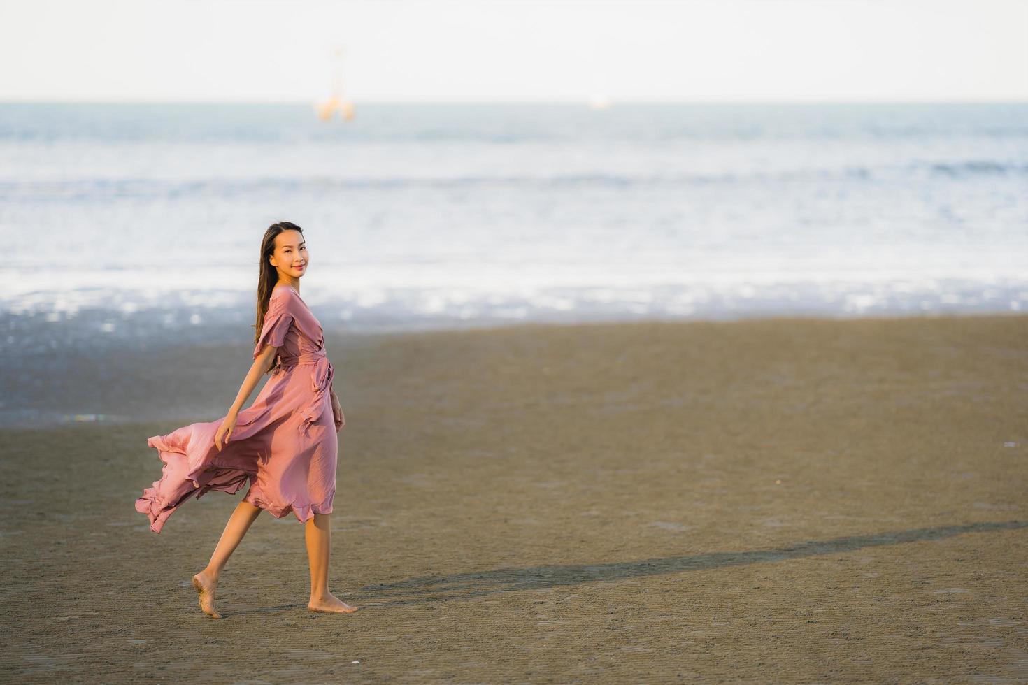 retrato, joven, hermoso, mujer asiática, caminar, sonrisa, y, feliz, en, el, playa, mar y océano foto