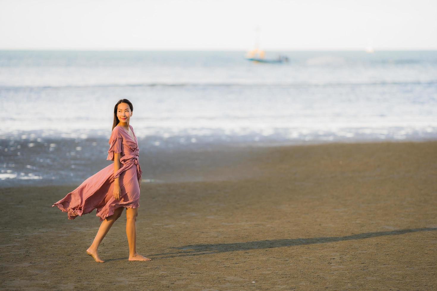 Portrait young beautiful asian woman walk smile and happy on the beach sea and ocean photo