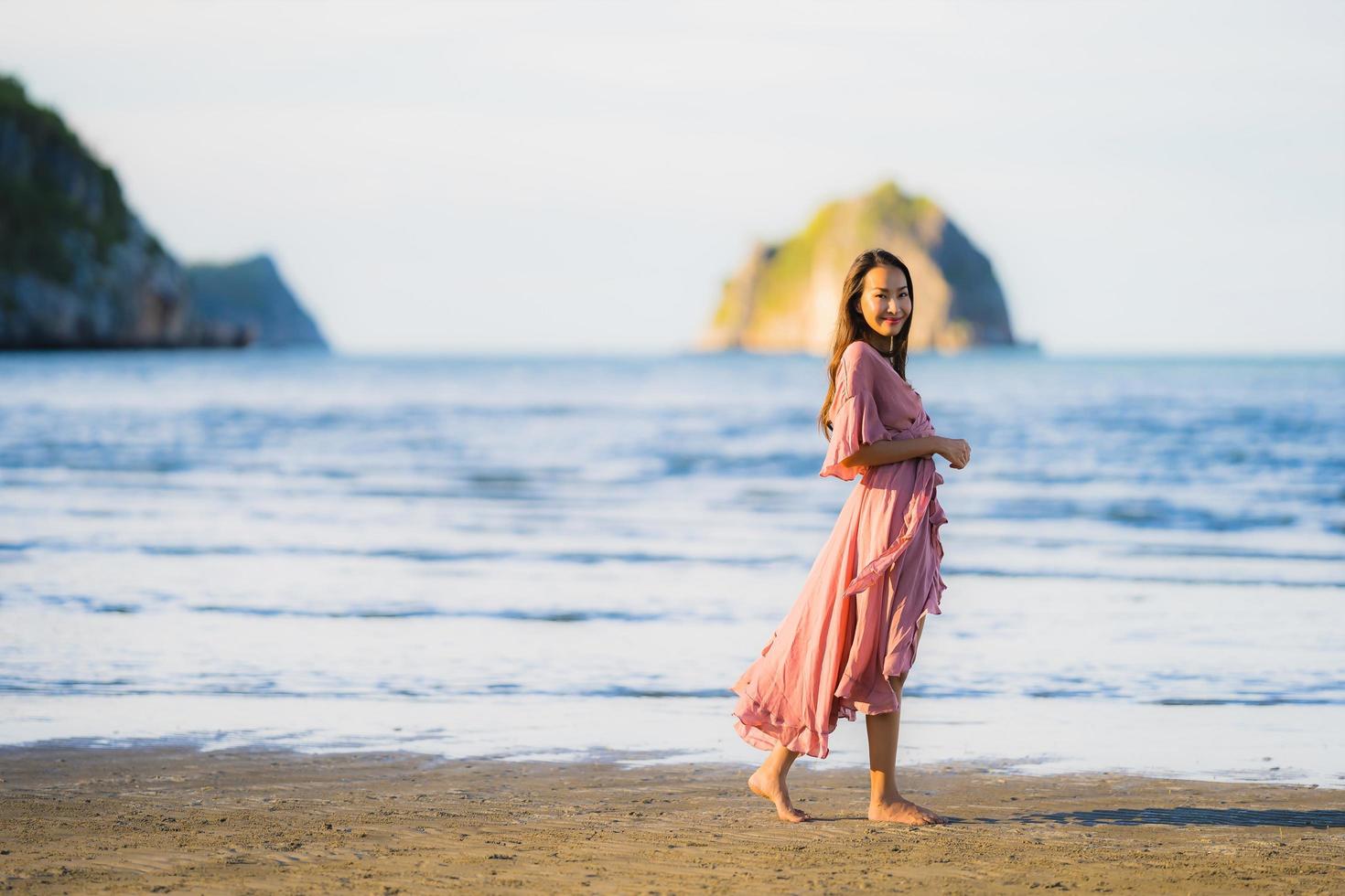 Portrait young beautiful asian woman walk smile and happy on the beach sea and ocean photo