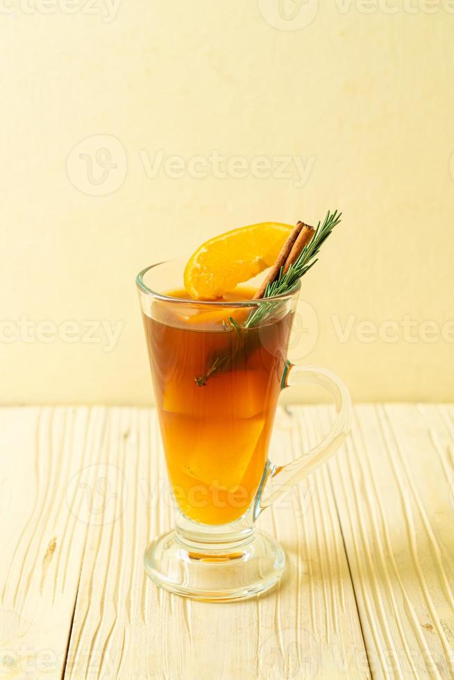 A glass of iced Americano black coffee and a layer of orange and lemon juice decorated with rosemary and cinnamon on a wood background photo