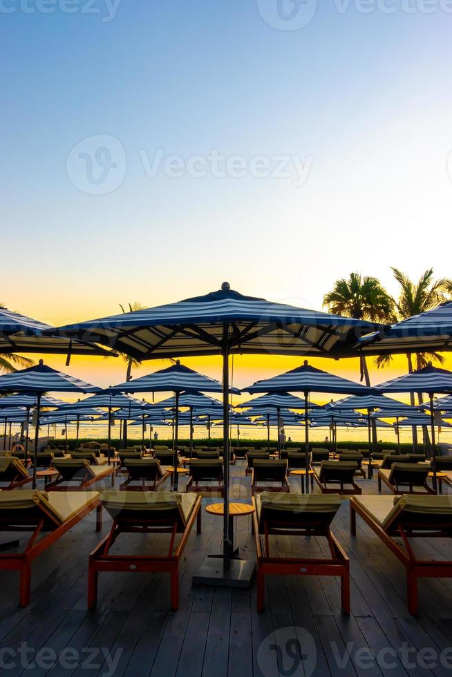 Umbrellas and chairs around outdoor swimming pool in hotel resort for holiday vacation travel background photo