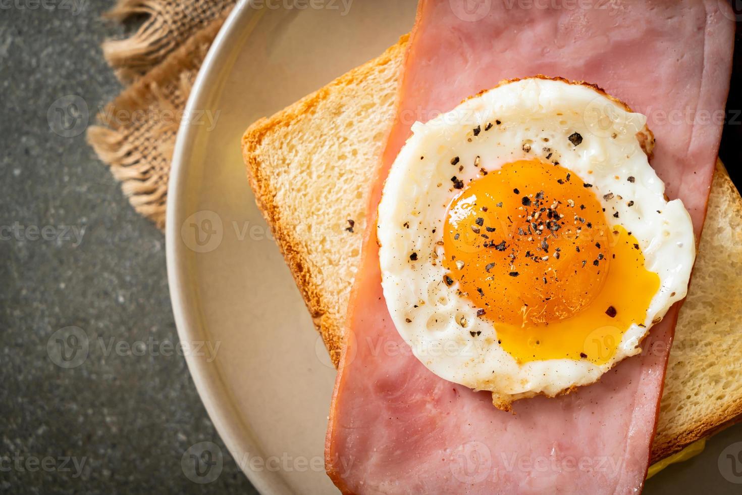 Homemade bread toasted cheese topped ham and fried egg with pork sausage for breakfast photo