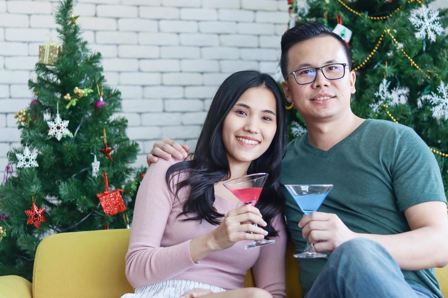 joven pareja asiática disfrutando de la navidad con champán foto