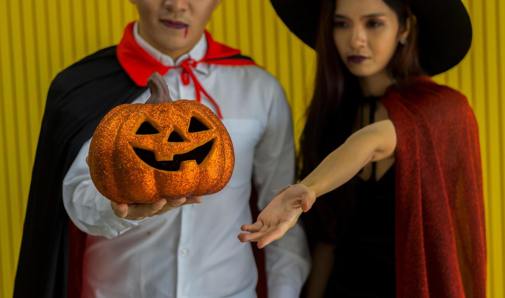 los hombres jóvenes se divierten bebiendo y celebrando la fiesta de halloween con calabaza naranja foto