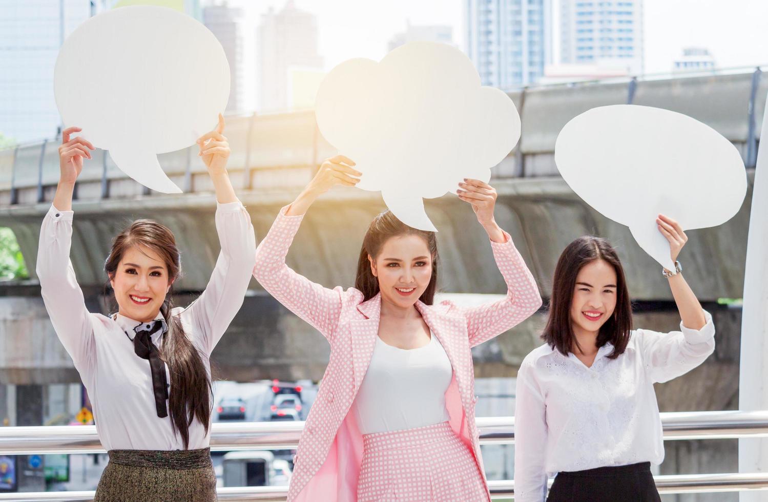 Grupo de mujeres empresarias asiáticas usan vestidos formales levantan carteles blancos en el centro de la ciudad foto