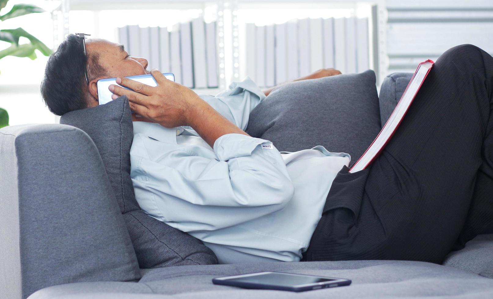 Elderly man talking on the phone Happily on sofa photo