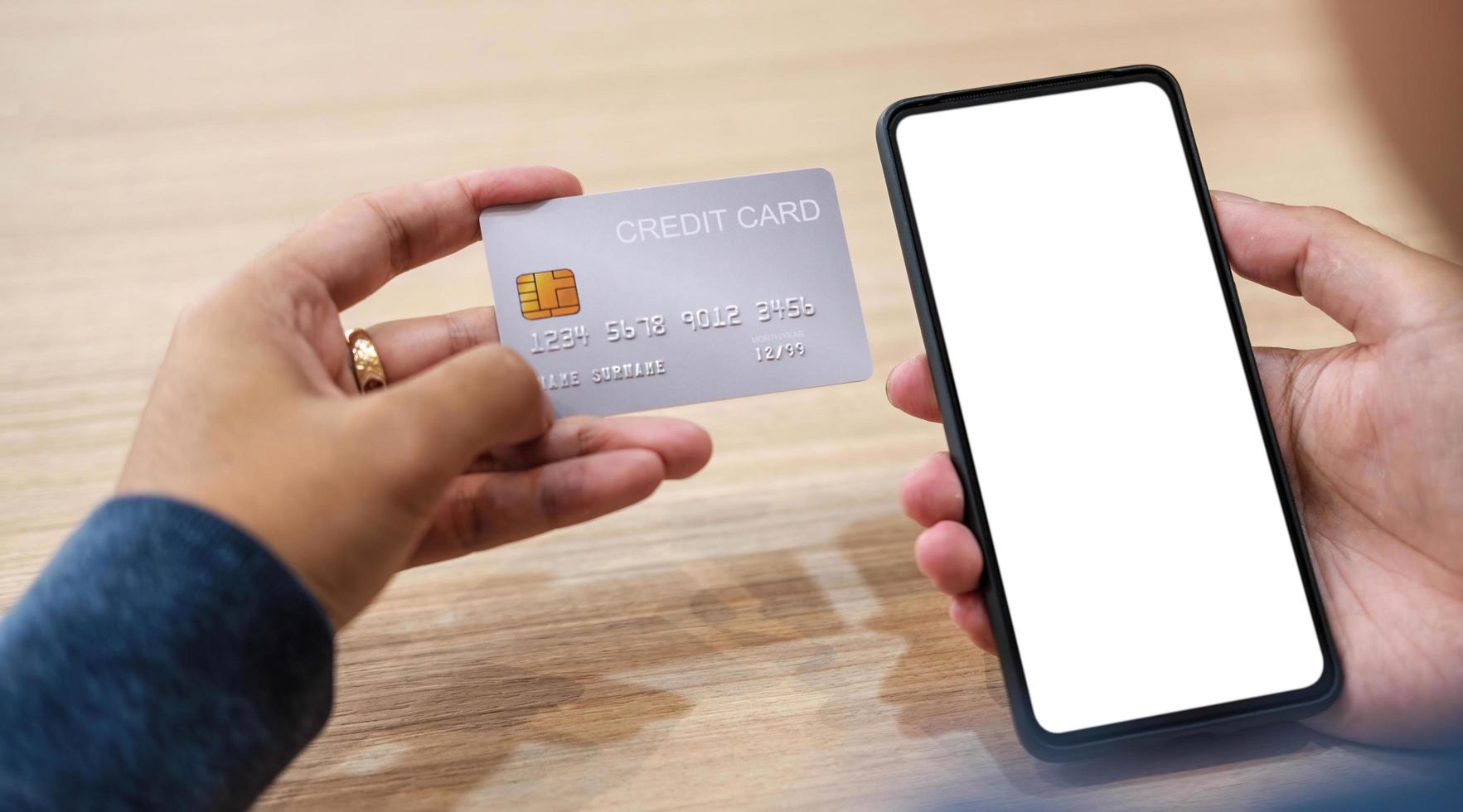 Cerrar la mano de la mujer de compras en línea con tarjeta de crédito mediante un teléfono inteligente en el café foto