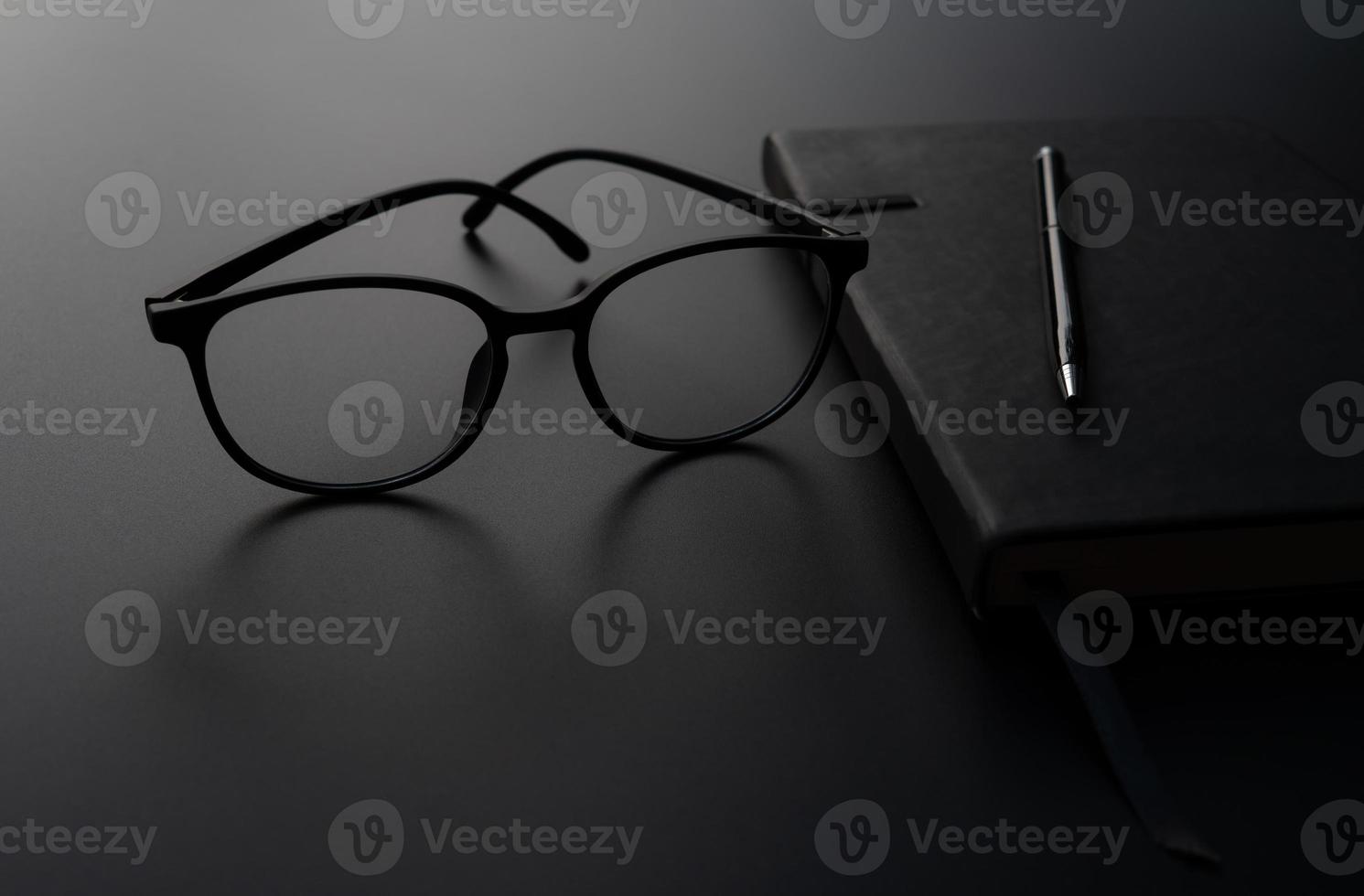 A picture of diary book of a student with eyeglasses on top on the black background photo