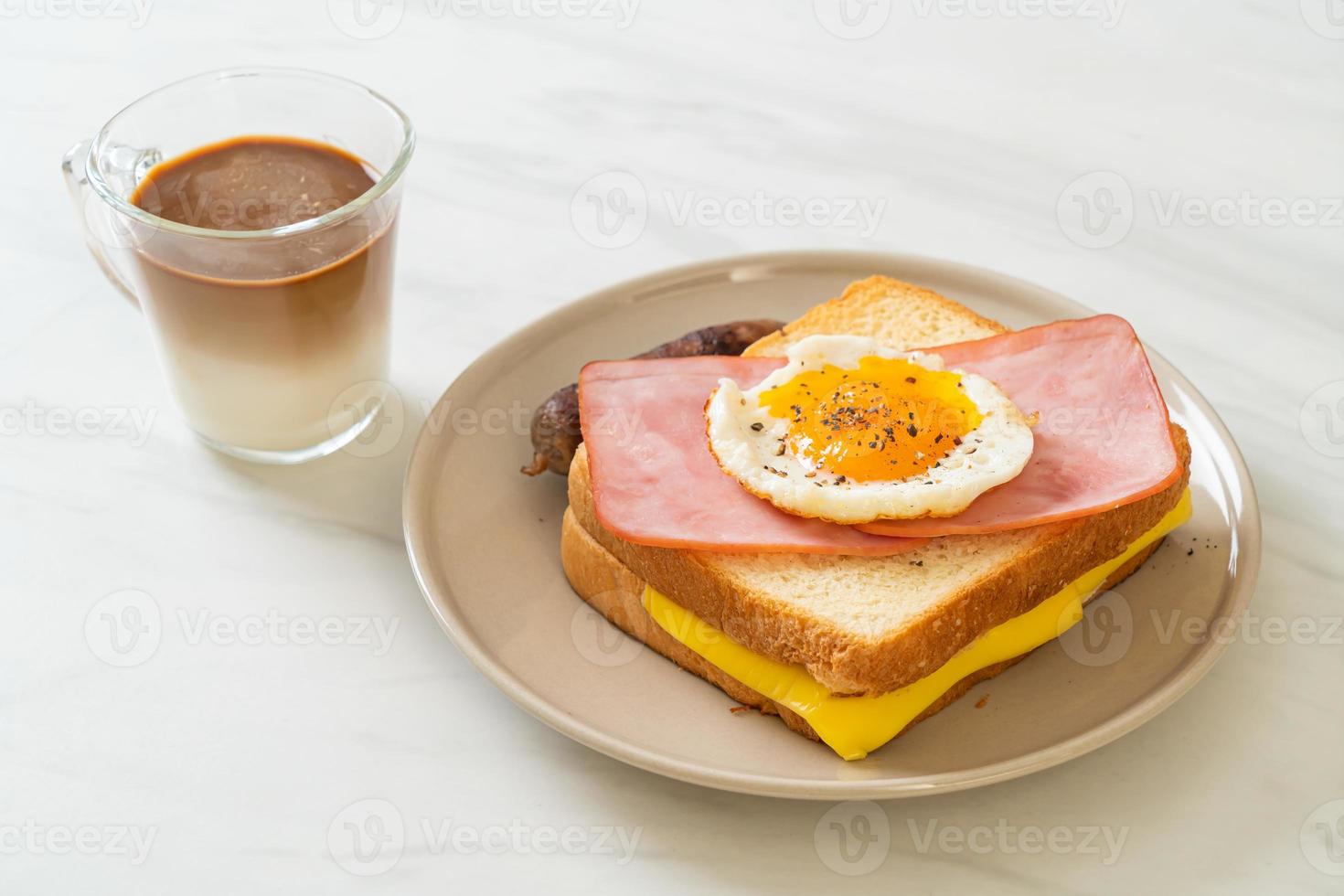 Homemade bread toasted cheese, topped ham, and fried egg with pork sausage for breakfast photo