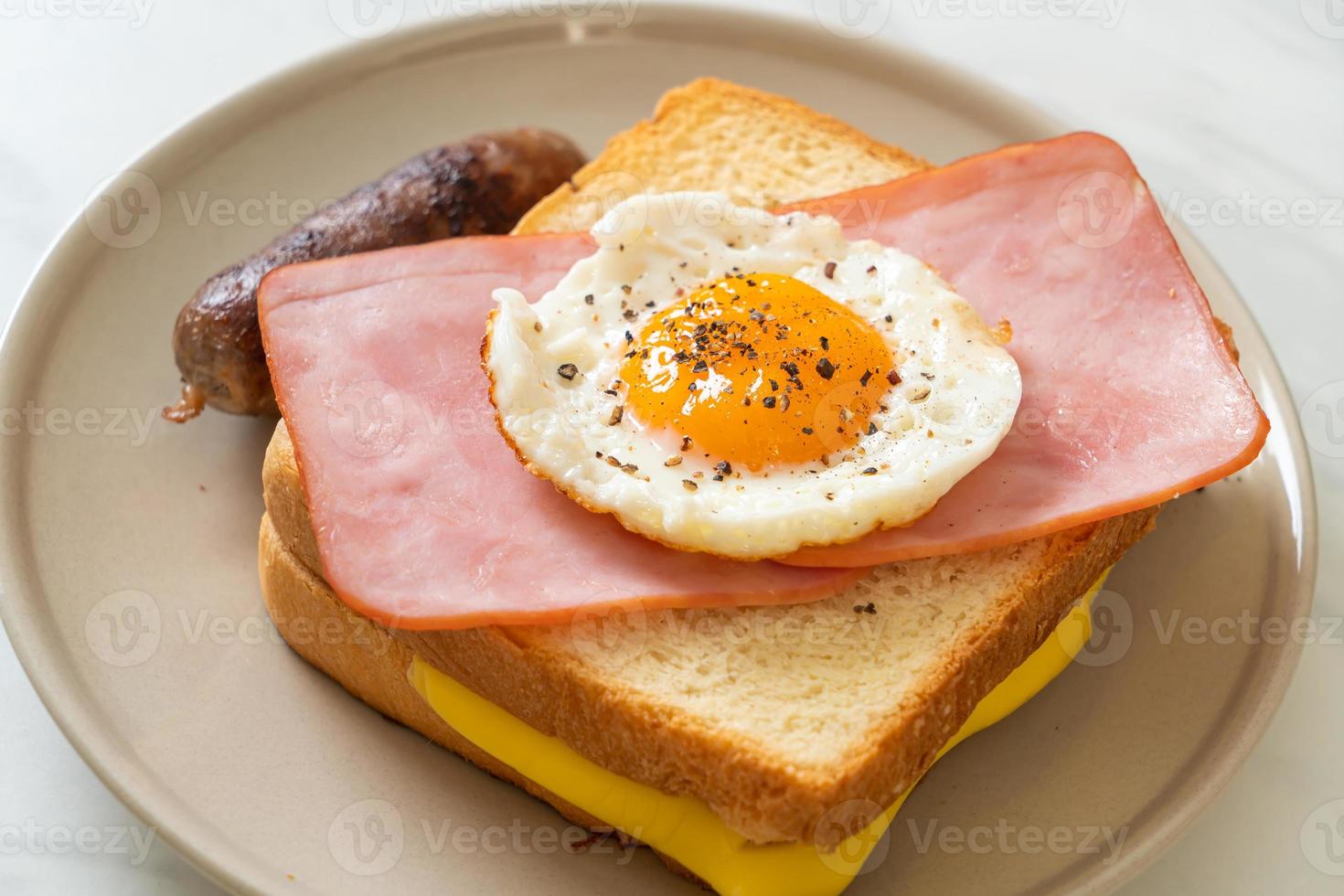 pan casero, queso tostado, jamón cubierto y huevo frito con salchicha de cerdo para el desayuno foto