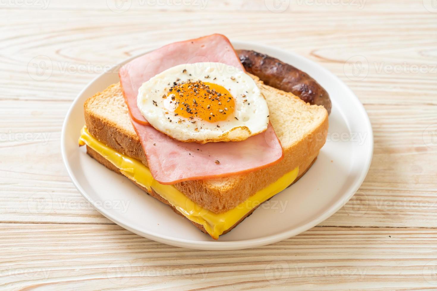 Homemade bread toasted cheese, topped ham, and fried egg with pork sausage for breakfast photo