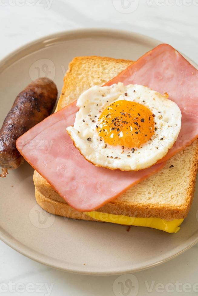 Homemade bread toasted cheese, topped ham, and fried egg with pork sausage for breakfast photo