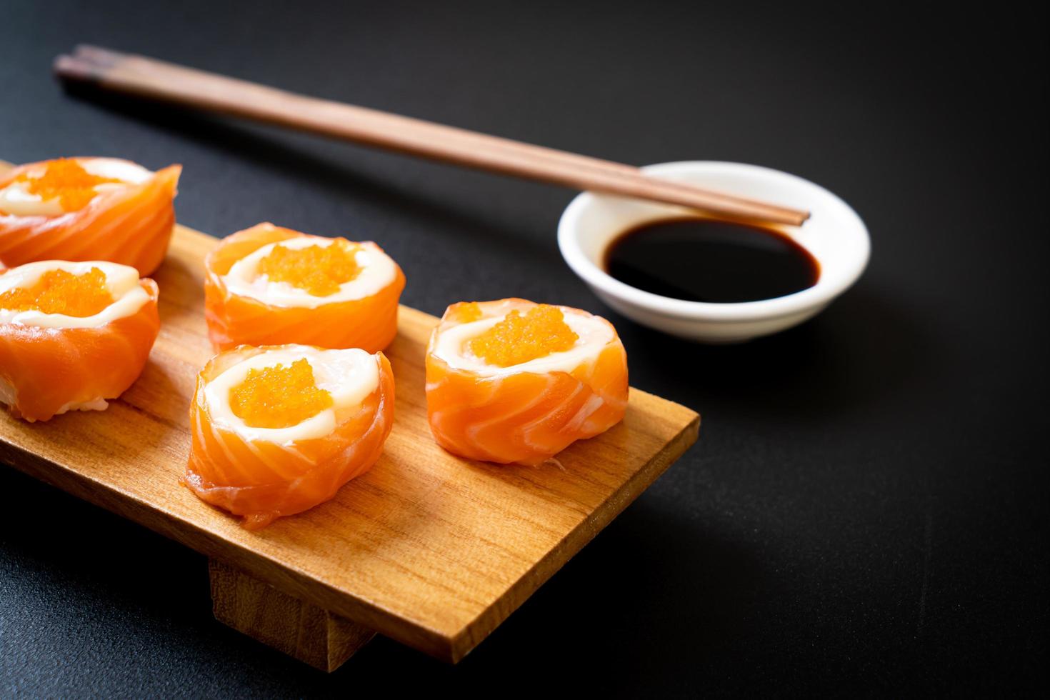 Rollo de sushi de salmón fresco con mayonesa y huevo de camarón - estilo de comida japonesa foto