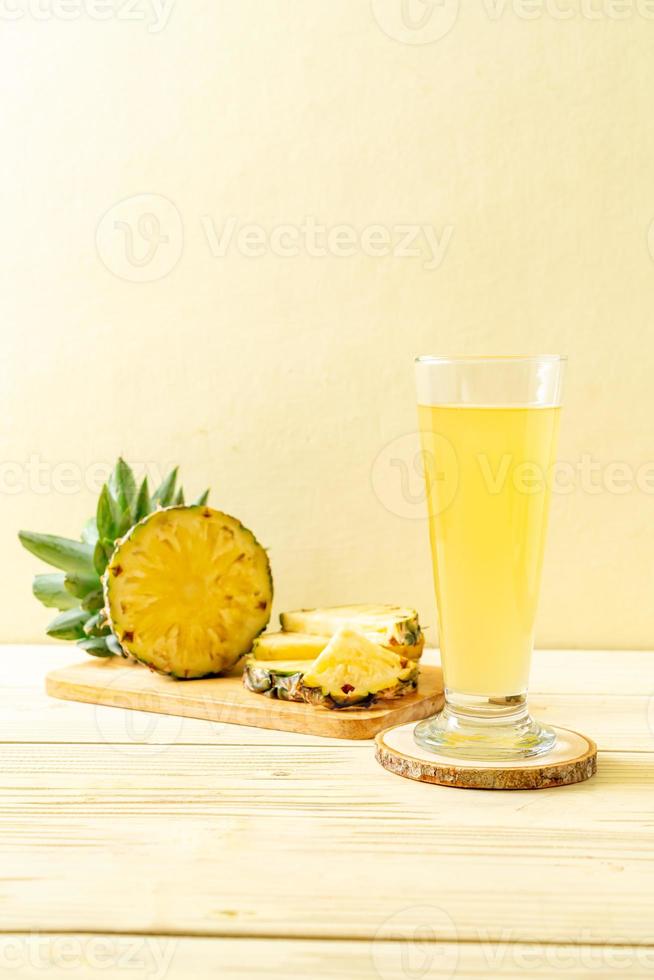 Jugo de piña fresca sobre fondo de madera foto