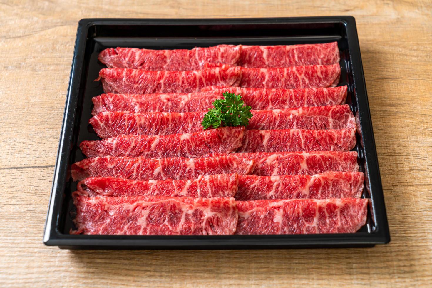 Carne fresca cruda en rodajas con textura de mármol servida para sukiyaki y shabu o yakiniku foto