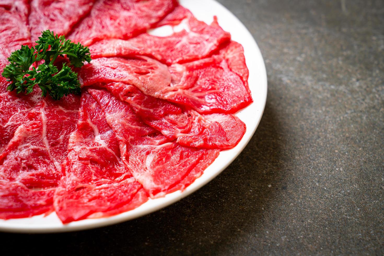 Carne fresca cruda en rodajas con textura de mármol servida para sukiyaki y shabu o yakiniku foto