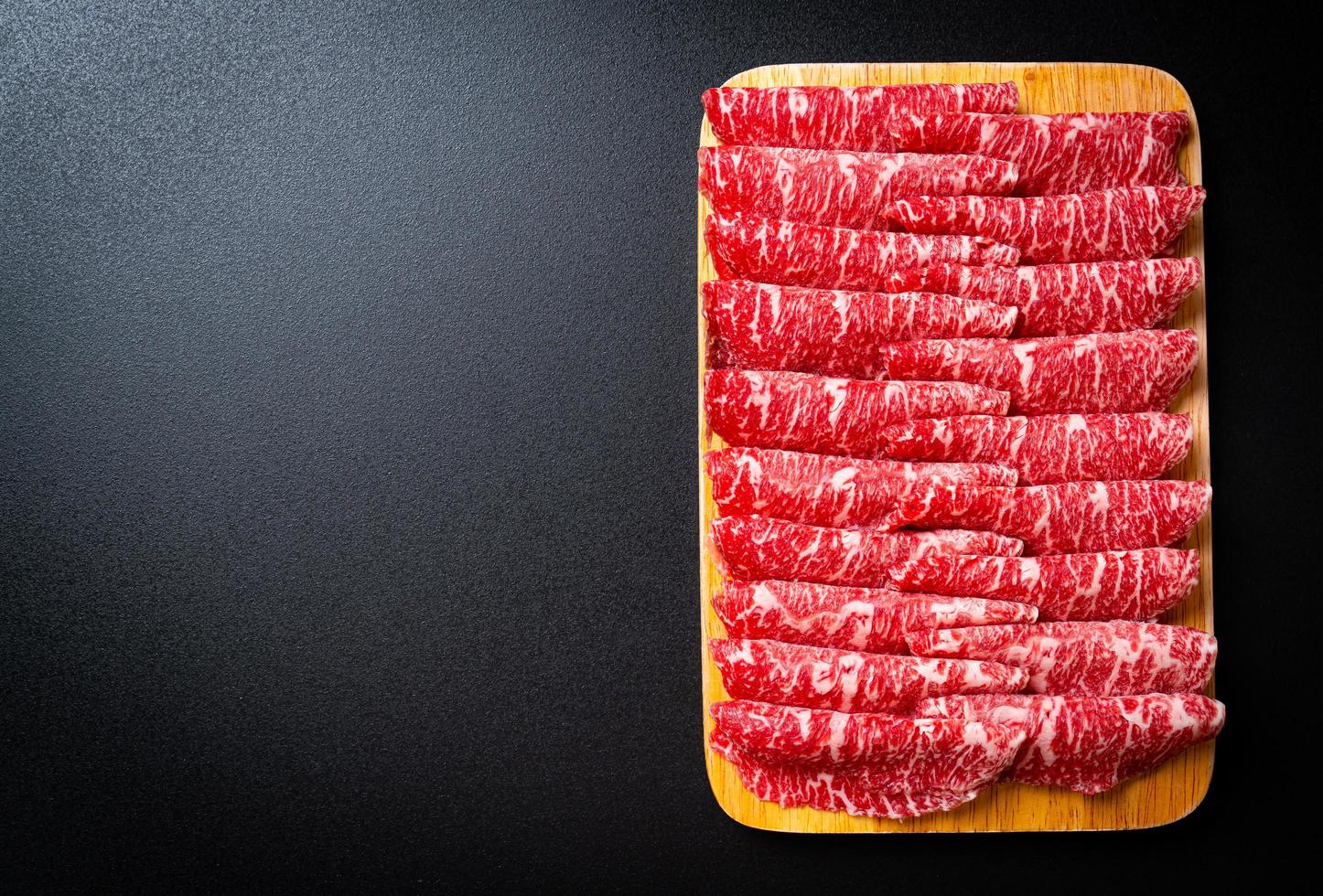 Carne fresca cruda en rodajas con textura de mármol servida para sukiyaki y shabu o yakiniku foto