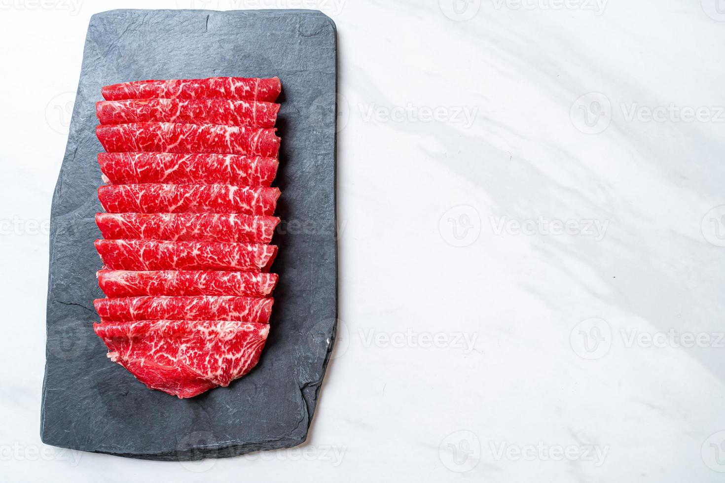 Carne fresca cruda en rodajas con textura de mármol servida para sukiyaki y shabu o yakiniku foto