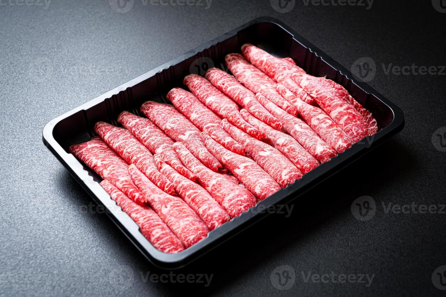 Carne fresca cruda en rodajas con textura de mármol servida para sukiyaki y shabu o yakiniku foto