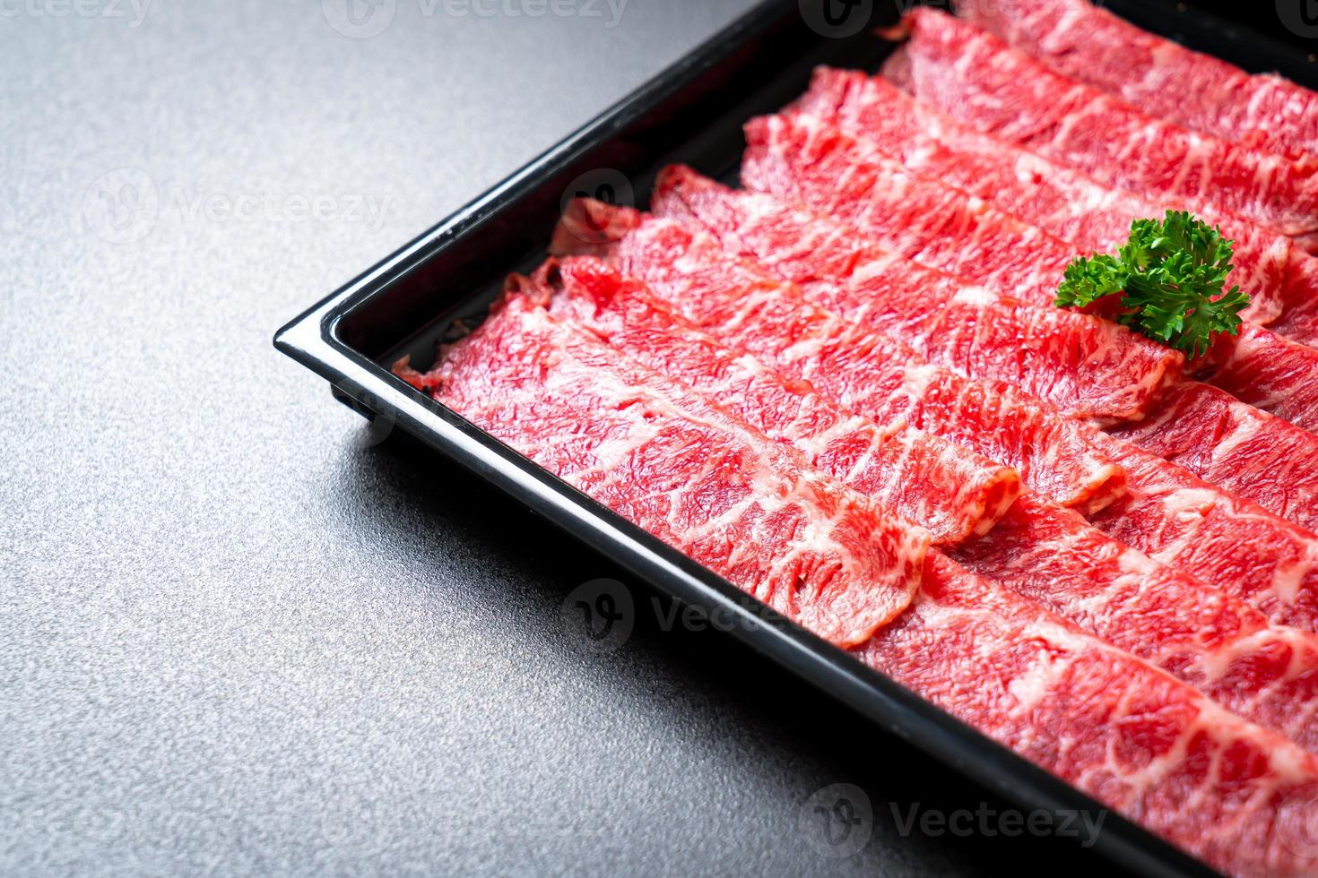 Carne fresca cruda en rodajas con textura de mármol servida para sukiyaki y shabu o yakiniku foto